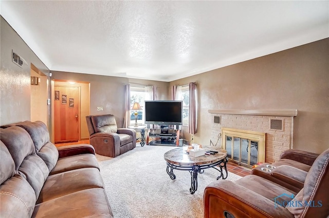 living room with visible vents, carpet flooring, a fireplace, and a textured ceiling