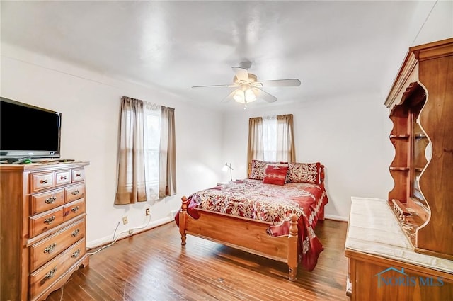 bedroom with baseboards, multiple windows, and wood finished floors