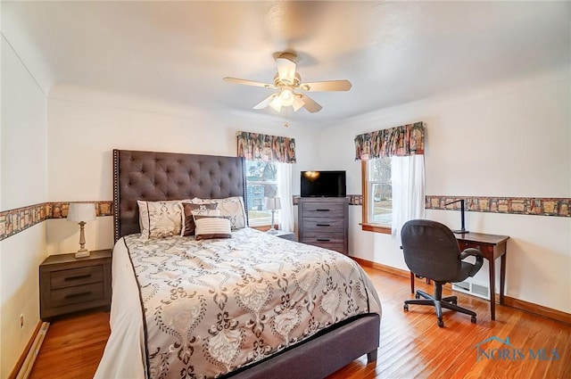 bedroom featuring wood finished floors, baseboards, and baseboard heating