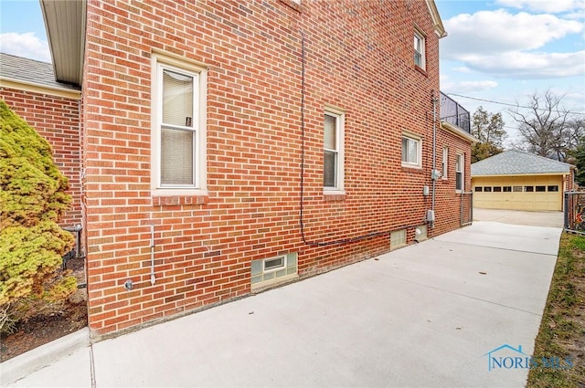 view of side of home with a garage, an outbuilding, and brick siding