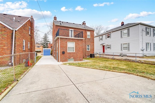 back of property with a balcony, fence, cooling unit, a yard, and brick siding