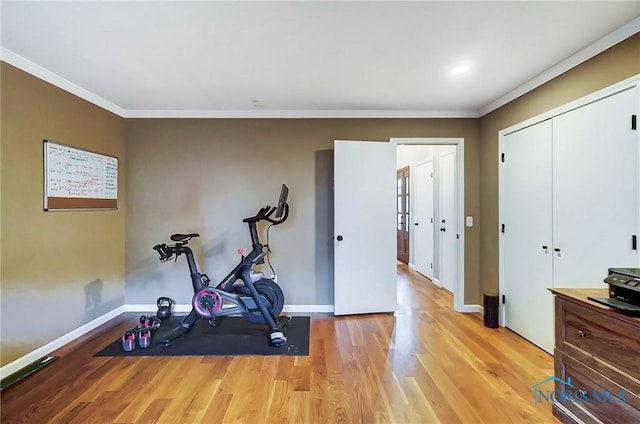 workout room with crown molding, light wood-type flooring, and baseboards