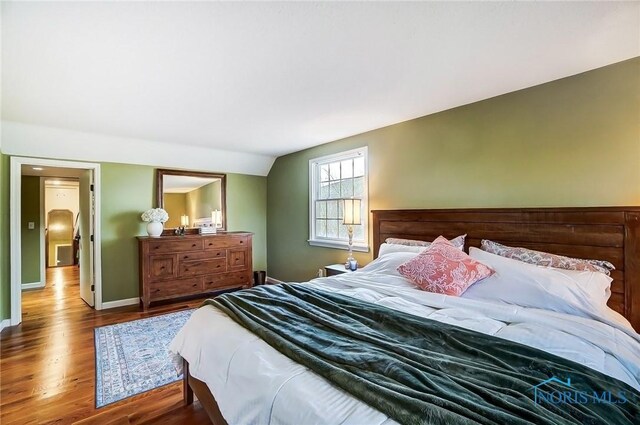 bedroom with baseboards, lofted ceiling, and wood finished floors