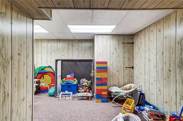 recreation room with carpet flooring, wood walls, and a paneled ceiling