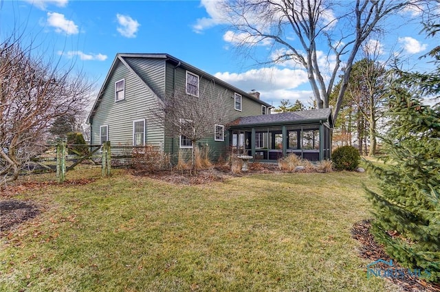 back of house with a lawn, a chimney, and a sunroom