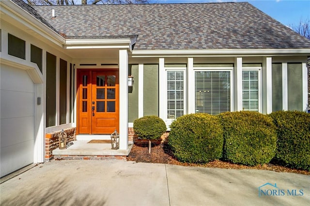 entrance to property with stucco siding and roof with shingles