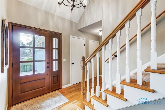 foyer entrance featuring stairway, lofted ceiling, baseboards, and wood finished floors