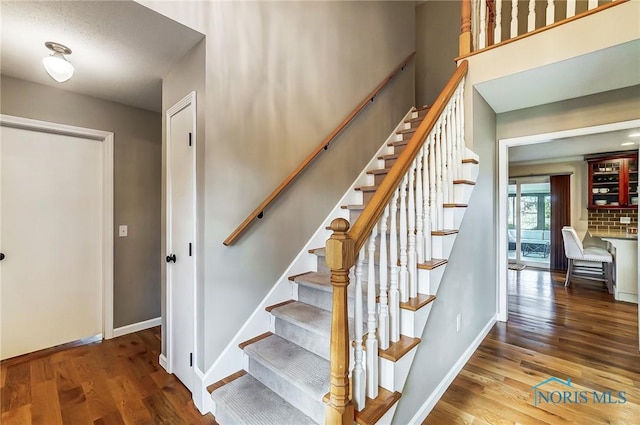 staircase featuring wood finished floors and baseboards