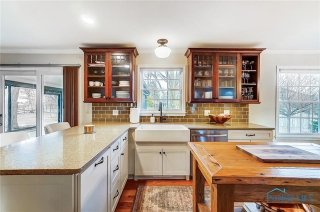 kitchen with a sink, backsplash, a peninsula, and ornamental molding