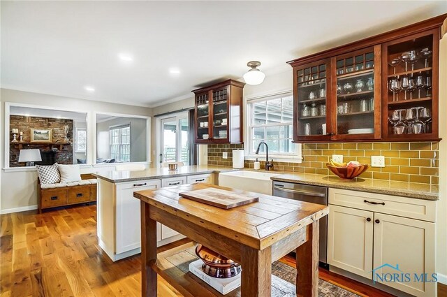 kitchen with tasteful backsplash, a sink, light wood-style flooring, a peninsula, and stainless steel dishwasher