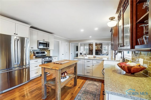 kitchen with light wood-style flooring, appliances with stainless steel finishes, glass insert cabinets, and a peninsula