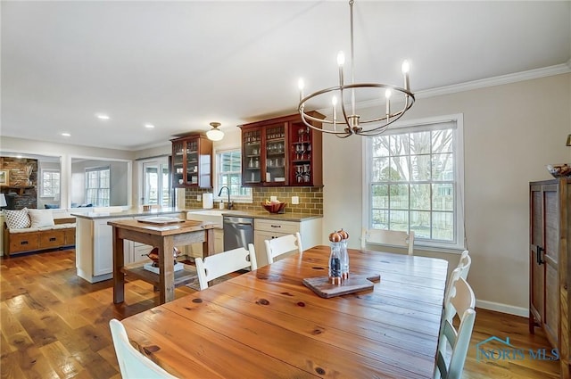 dining area with crown molding, a notable chandelier, wood finished floors, and baseboards