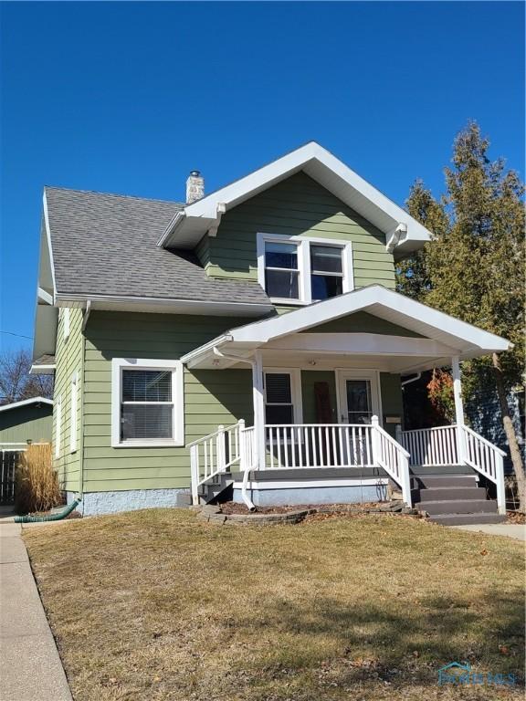 view of front of home featuring a front lawn, a porch, a chimney, and roof with shingles