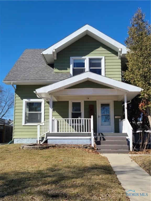 view of front of home featuring a porch, a front lawn, and roof with shingles