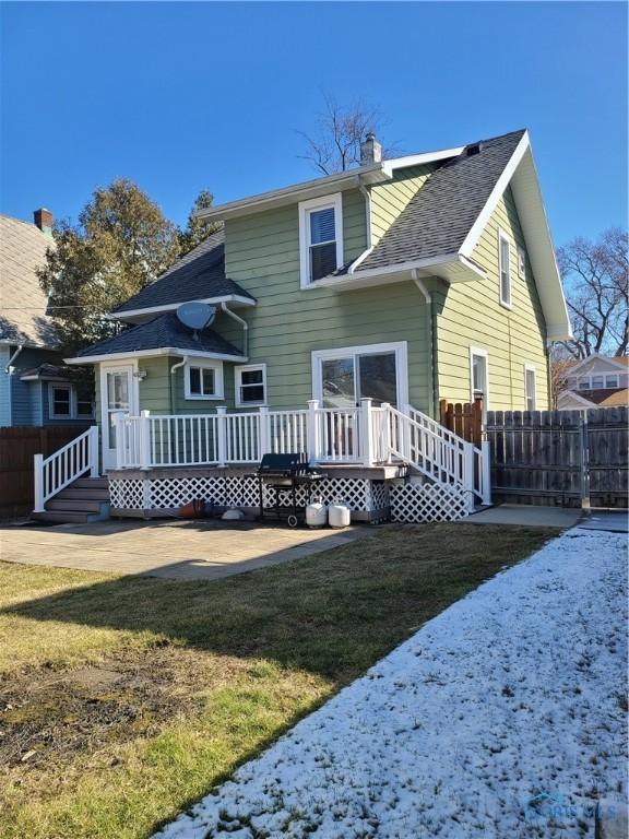 back of property with a lawn, a deck, and fence