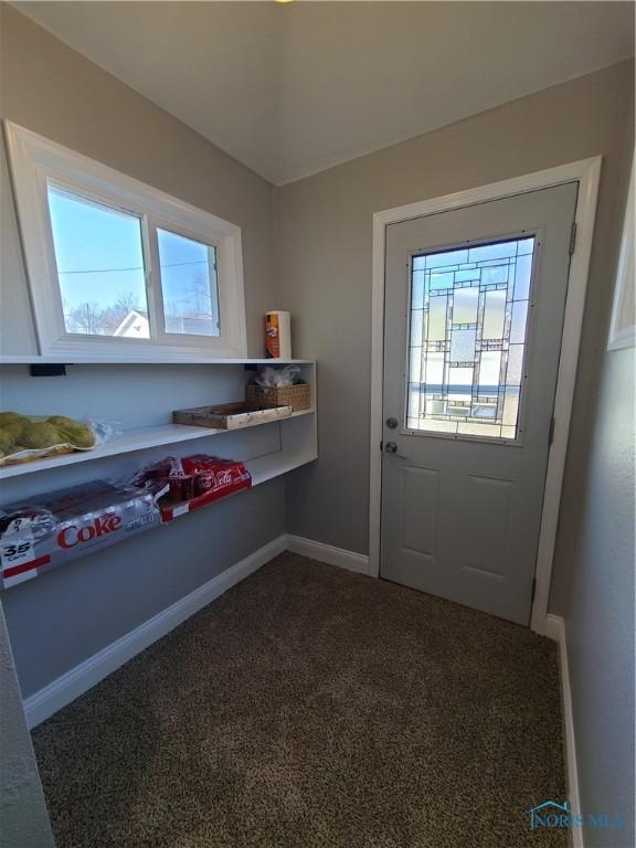 entryway featuring baseboards and dark carpet