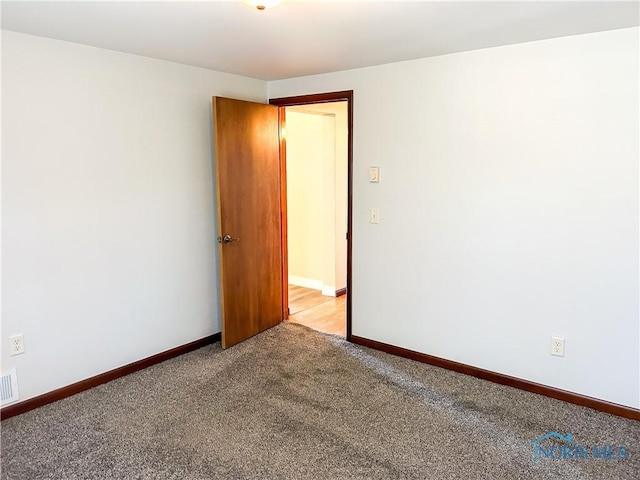 empty room featuring light carpet, visible vents, and baseboards