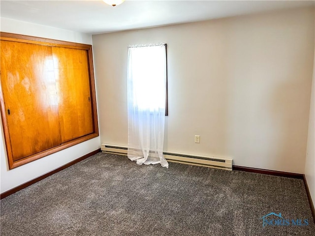 carpeted empty room featuring baseboards and a baseboard radiator