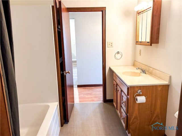 bathroom featuring vanity, baseboards, and a bathing tub