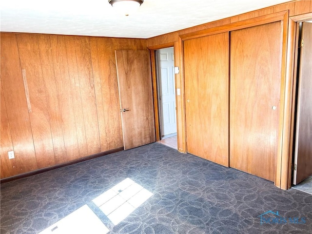 unfurnished bedroom with a closet and wood walls