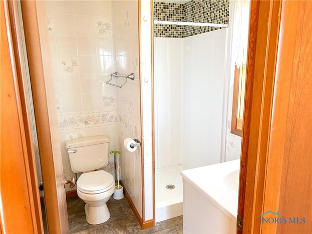 bathroom featuring vanity, toilet, tile walls, and a shower stall