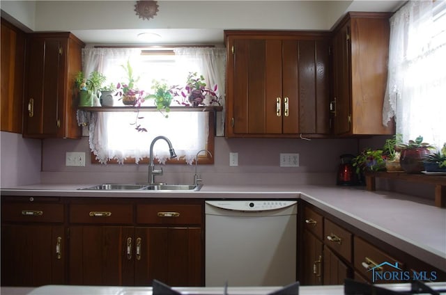 kitchen with a sink, light countertops, and white dishwasher