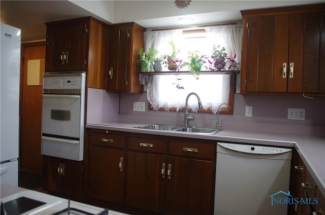 kitchen with a sink, white appliances, a warming drawer, and light countertops