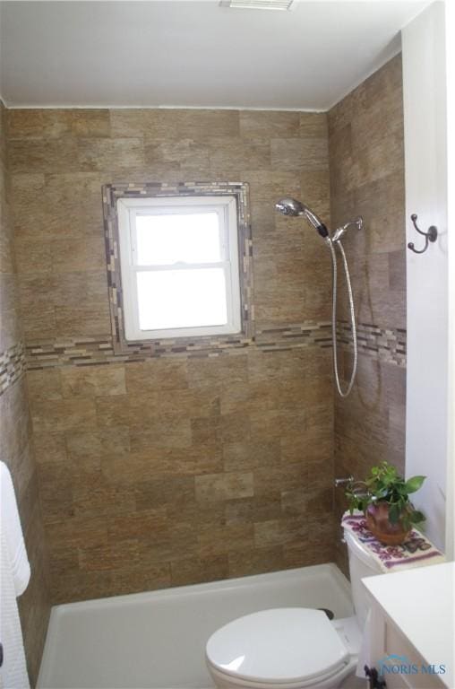 bathroom featuring vanity, toilet, and tiled shower