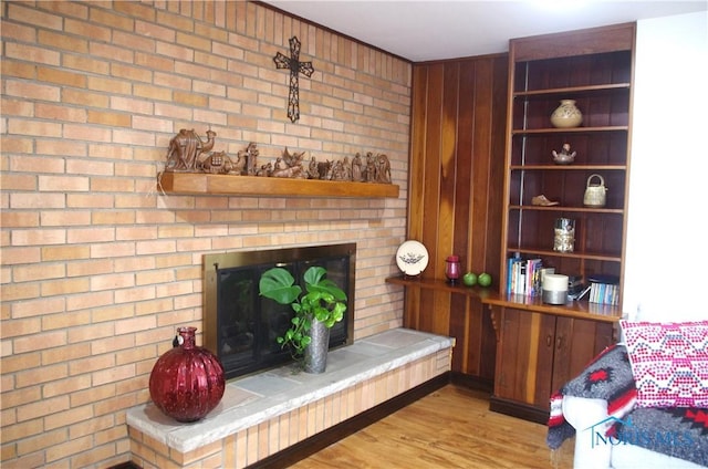 living room featuring a brick fireplace and wood finished floors