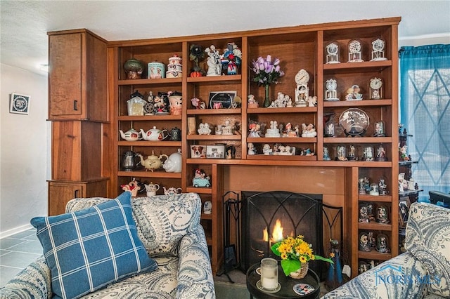 sitting room with baseboards and a lit fireplace