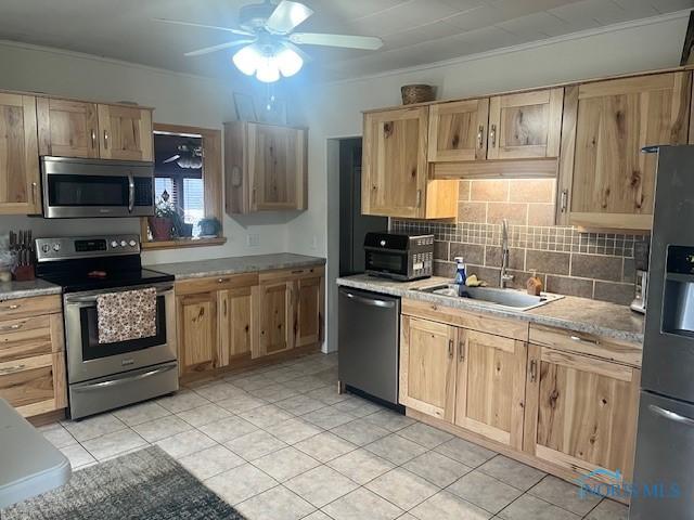 kitchen with light brown cabinetry, tasteful backsplash, appliances with stainless steel finishes, and a sink