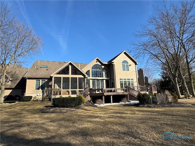 back of property with a wooden deck, a yard, and a sunroom