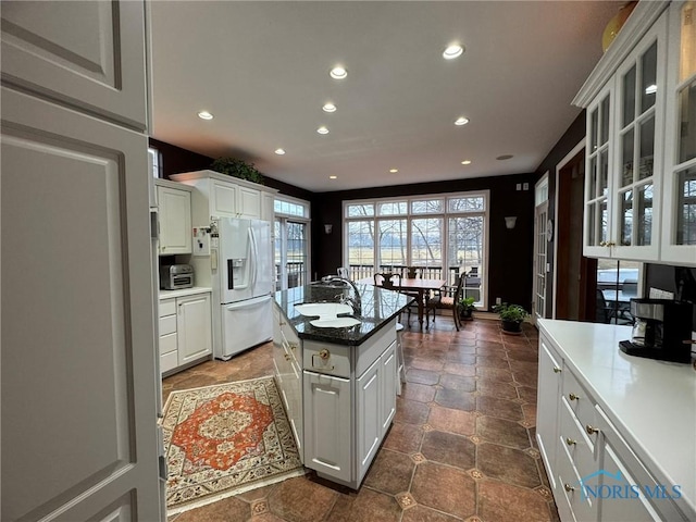 kitchen with glass insert cabinets, white cabinets, recessed lighting, and white fridge with ice dispenser