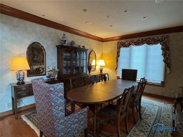 dining room featuring ornamental molding, baseboards, and wood finished floors