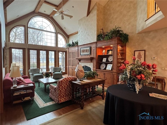 living room with a ceiling fan, wood finished floors, high vaulted ceiling, a fireplace, and beamed ceiling