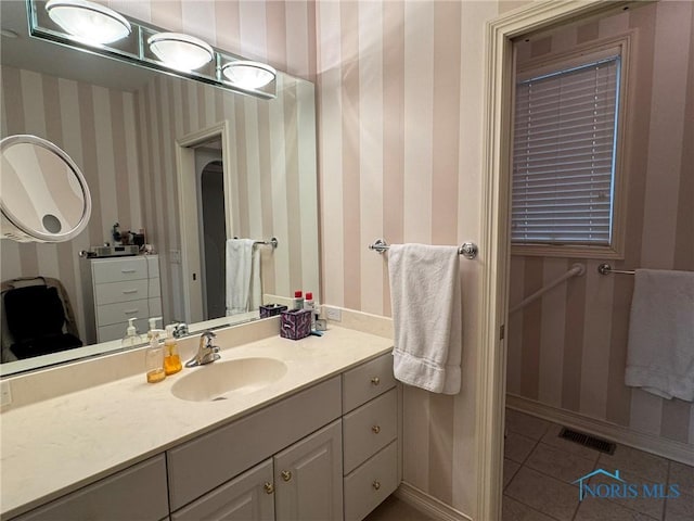 bathroom featuring vanity, baseboards, visible vents, wallpapered walls, and tile patterned floors