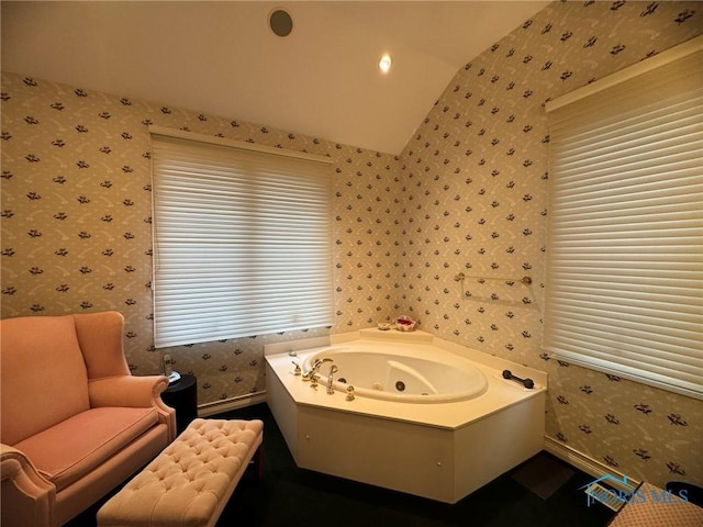 bathroom with a jetted tub, vaulted ceiling, and wallpapered walls