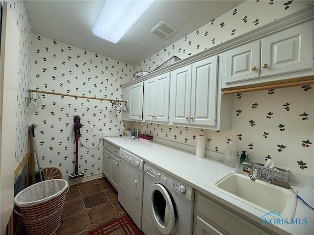 laundry area featuring visible vents, washing machine and clothes dryer, wallpapered walls, cabinet space, and a sink