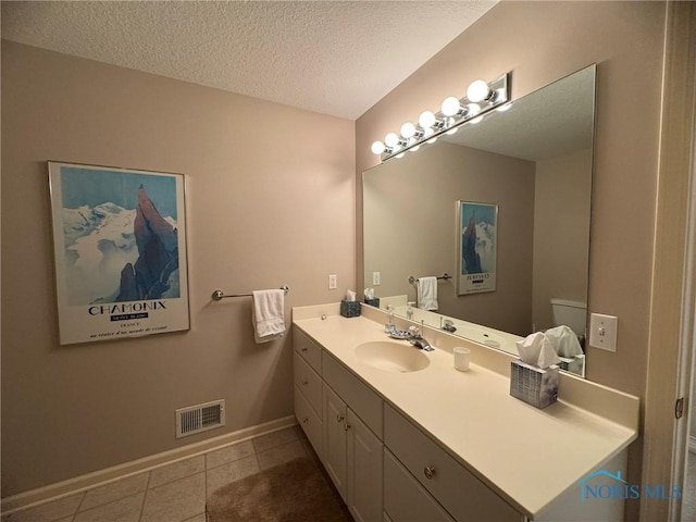 bathroom with visible vents, baseboards, vanity, tile patterned floors, and a textured ceiling