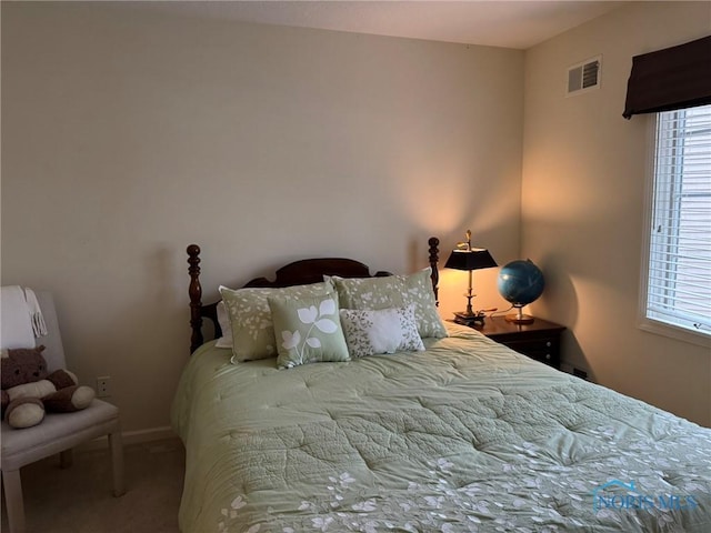 carpeted bedroom featuring visible vents, multiple windows, and baseboards