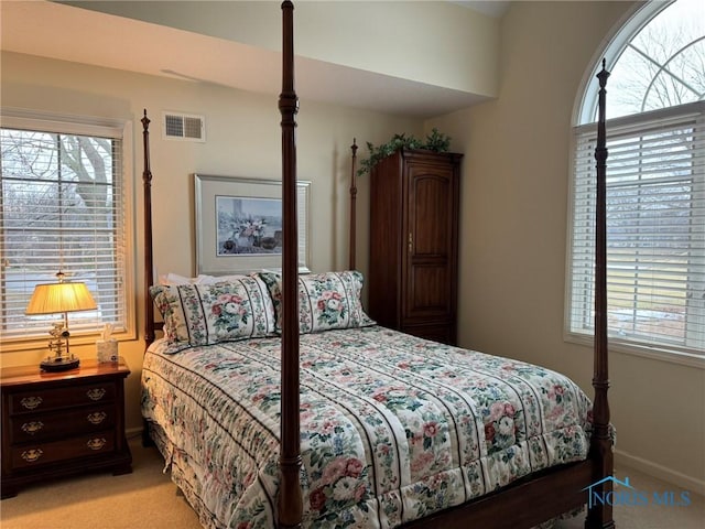 bedroom with visible vents, multiple windows, light colored carpet, and baseboards