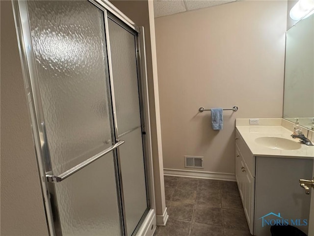 full bathroom featuring visible vents, a stall shower, a drop ceiling, baseboards, and vanity