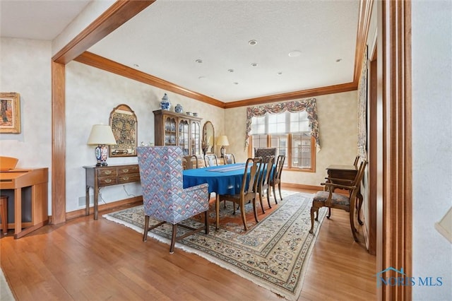 dining space with visible vents, baseboards, wood finished floors, and ornamental molding