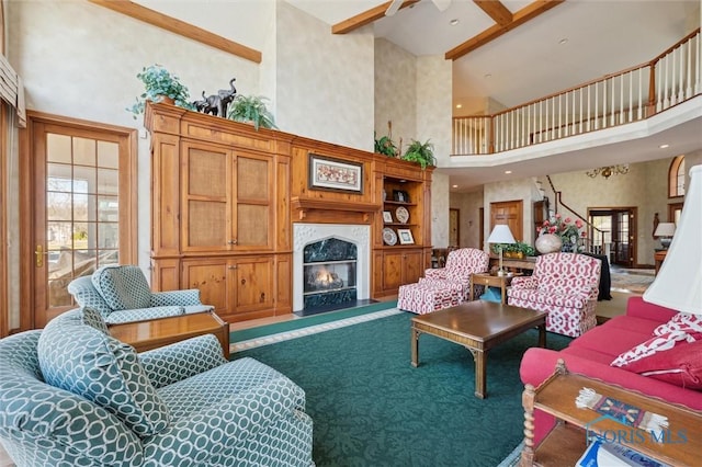living room with plenty of natural light, beam ceiling, a towering ceiling, and a fireplace with flush hearth