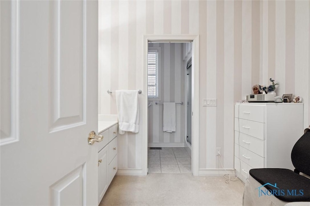 bathroom featuring vanity, baseboards, wallpapered walls, a stall shower, and tile patterned flooring