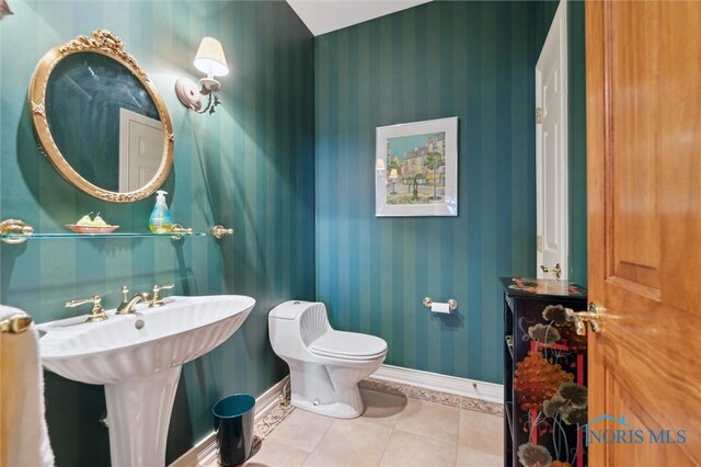 half bath with tile patterned floors, toilet, wallpapered walls, and baseboards