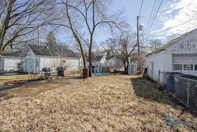 view of yard with fence, central AC, a storage shed, an outdoor structure, and a patio