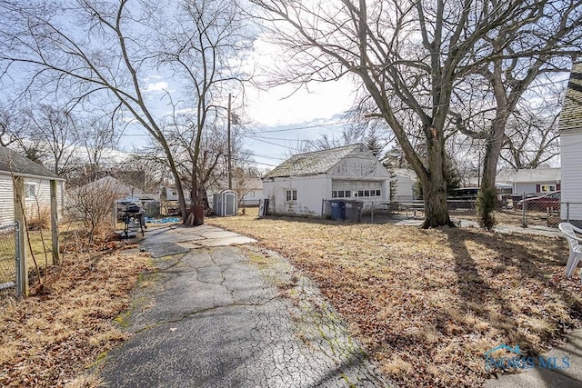 view of property exterior featuring an outbuilding, fence, and driveway