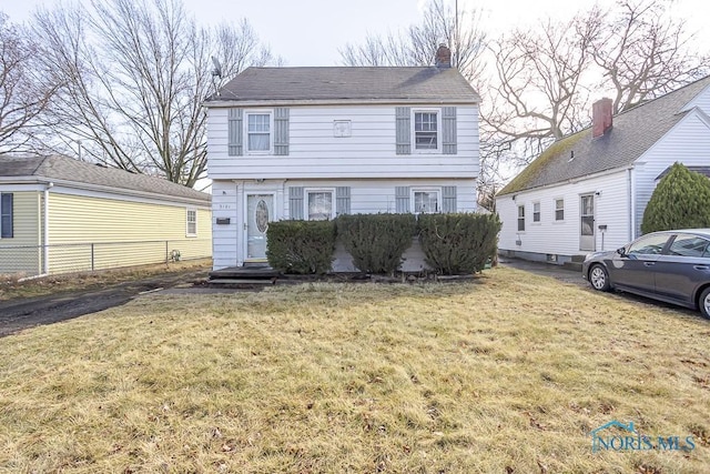 colonial home featuring a chimney, a front yard, and fence