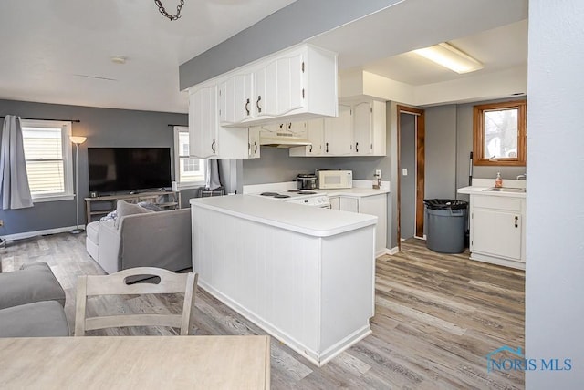 kitchen featuring white microwave, light countertops, under cabinet range hood, range, and open floor plan